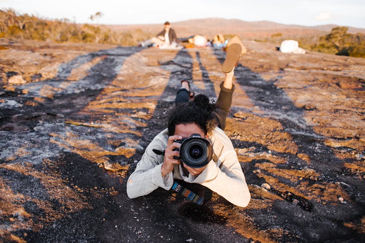 Person Lying On Ground Taking Picture With Camera