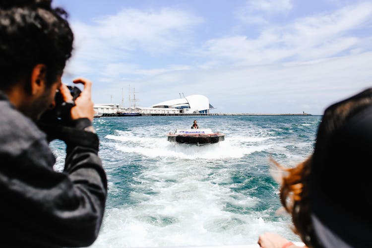 Man Taking Photo Of Woman On Motorboat