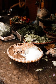 A vibrant outdoor market scene showcasing baskets of fresh vegetables and noodles on a city street.