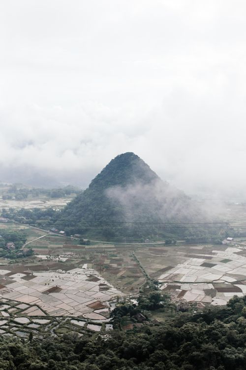 Free A breathtaking view of a mist-covered mountain and vast countryside fields. Stock Photo