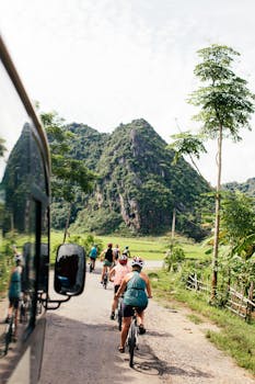 Group of cyclists biking through a picturesque countryside road with mountains.