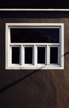 Exterior of residential house with shadow and brown plaster with small white windows located on street with bright sunlight in town