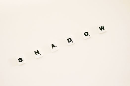 Scrabble tiles spelling 'SHADOW' on a white background, perfect for design concepts.
