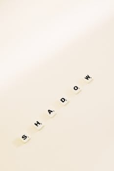 Scrabble tiles spelling 'SHADOW' on a white background, showcasing minimalism and wordplay.