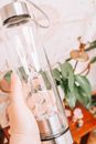 Person Holding Clear Glass Bottle