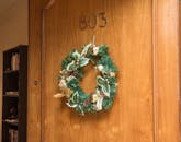 803号房间的木制门上挂着一个装饰性圣诞花环，增添了节日氛围