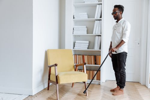 Free African American man with walking stick in stylish room showcasing disability representation. Stock Photo
