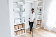 Man in White Dress Shirt and Black Pants Standing on Brown Wooden Floor