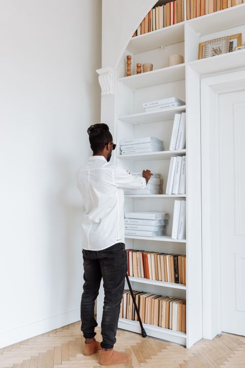 Free A visually impaired man reading Braille books in a modern library setting. Stock Photo