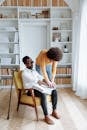 Man in White Dress Shirt Sitting on Chair Beside Woman in White Long Sleeve Shirt