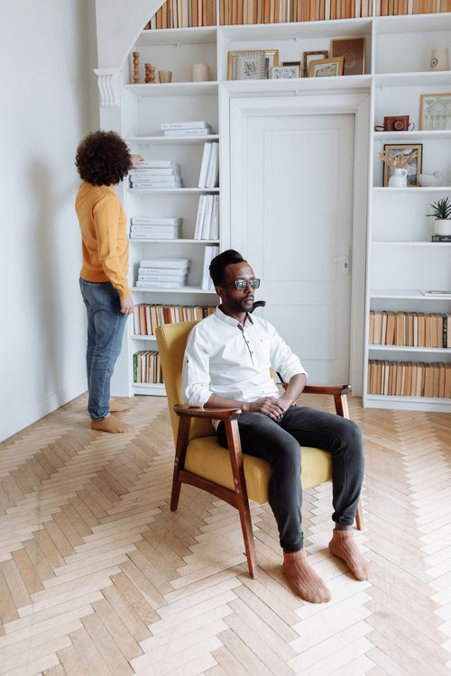 Free Blind man sitting in a chair reading Braille in a modern library with stylish bookshelves. Stock Photo