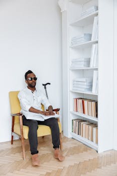 A visually impaired man reads Braille in a stylish library setting, emphasizing sensory perception.