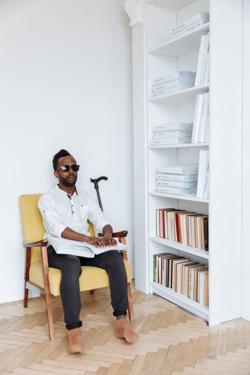 Free A visually impaired man reads Braille in a stylish library setting, emphasizing sensory perception. Stock Photo