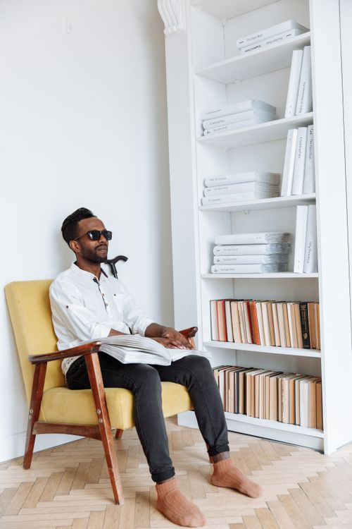 Free Visually impaired African American man reads a Braille book while sitting in a stylish room. Stock Photo