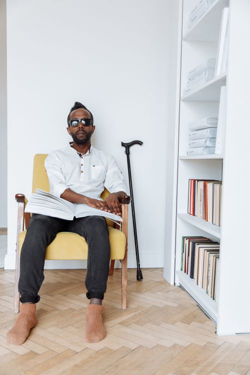 Free African American man reading a braille book indoors, showcasing visual impairment awareness. Stock Photo