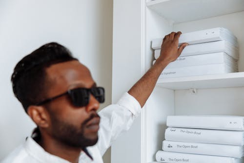 A Man Getting a Book in a Wooden Shelf