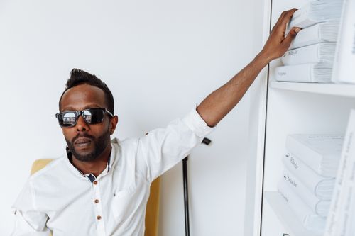 Free African American man with visual impairment selecting books in a modern library. Stock Photo