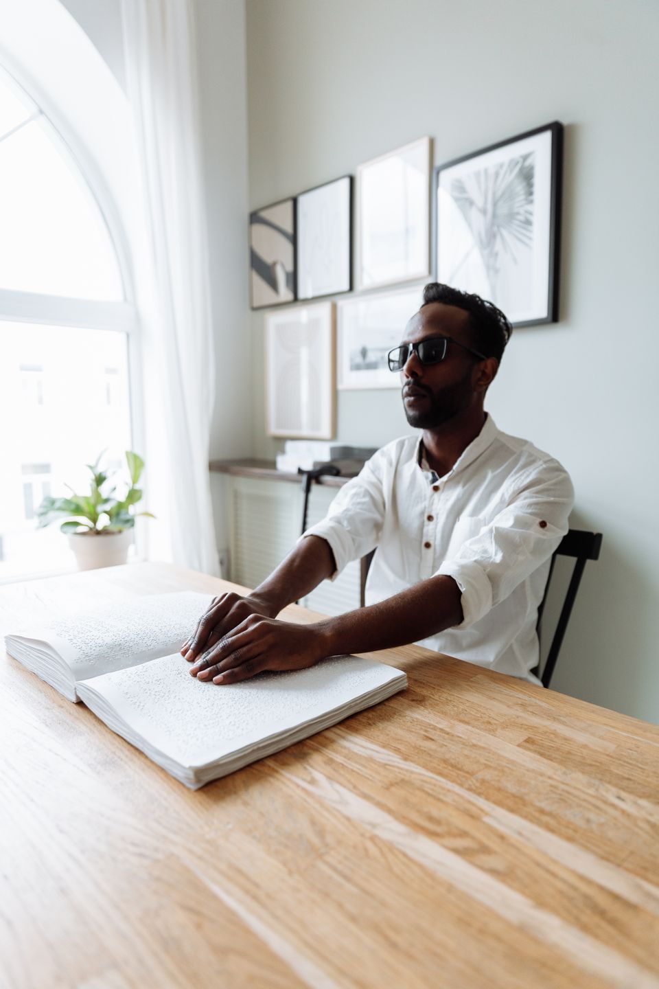 A visually impaired man reading braille at his desk