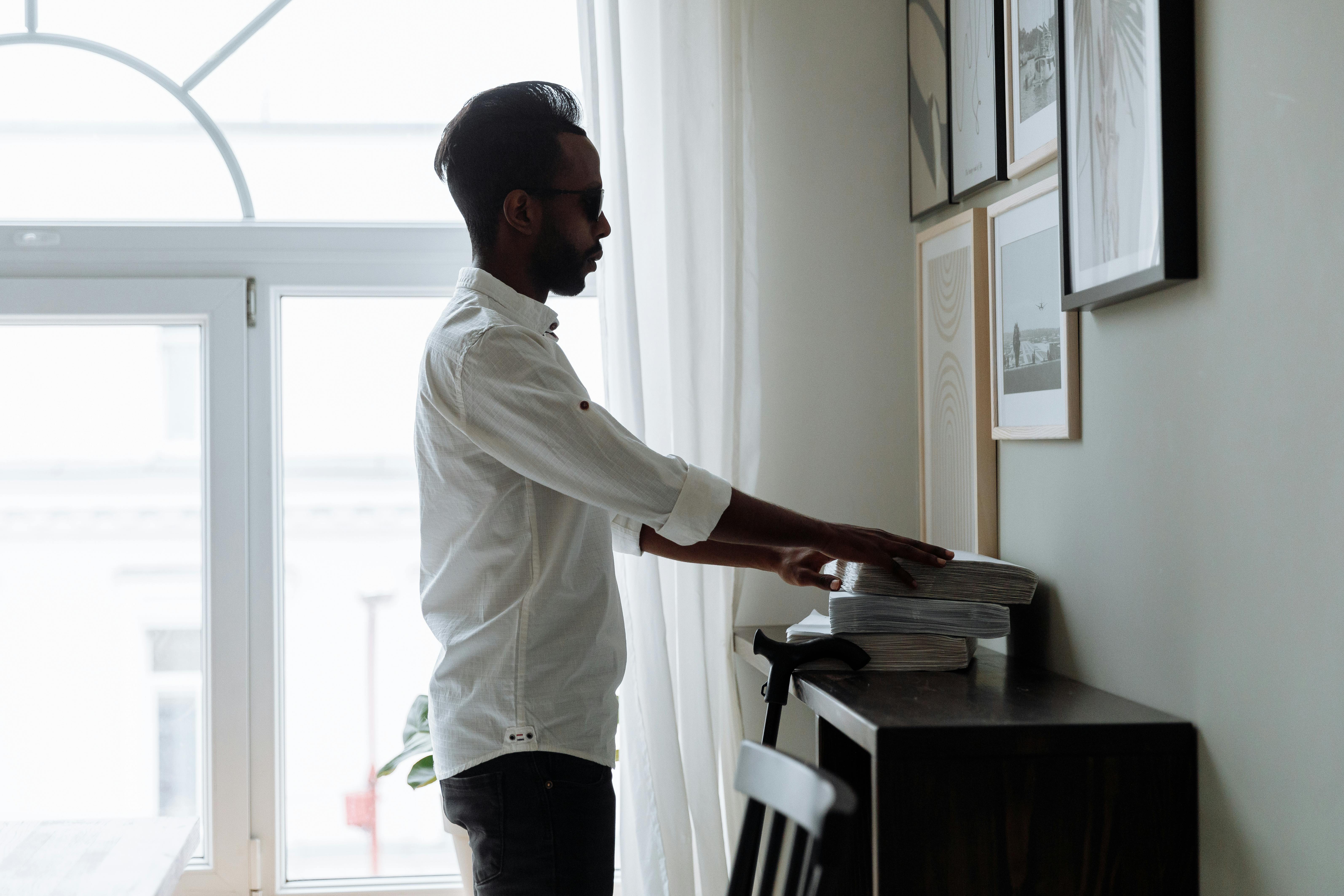 man in white dress shirt and black pants standing near window