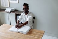 Man in White Button Up Shirt Wearing Black Sunglasses Sitting on Chair