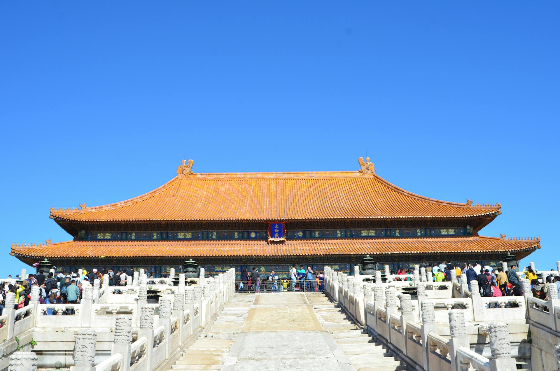 Tourists visiting the historic Forbidden City in Beijing, showcasing traditional Chinese architecture under a clear blue sky.