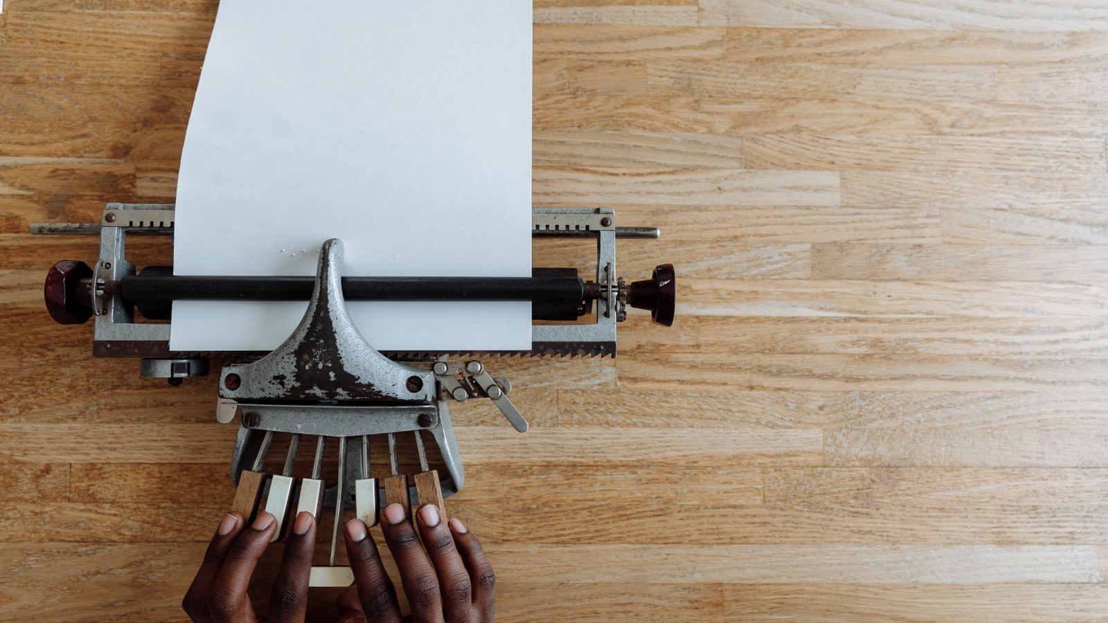 Hands positioned on a braille typewriter with paper loaded