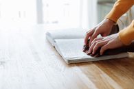 Close-up of hands reading a Braille book, depicting visual impairment education.