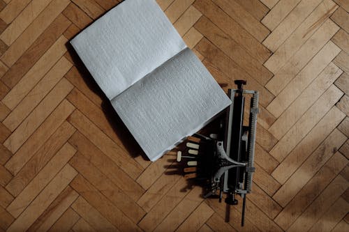 Braille Book and Blista Brailler Writer on Wooden Surface 