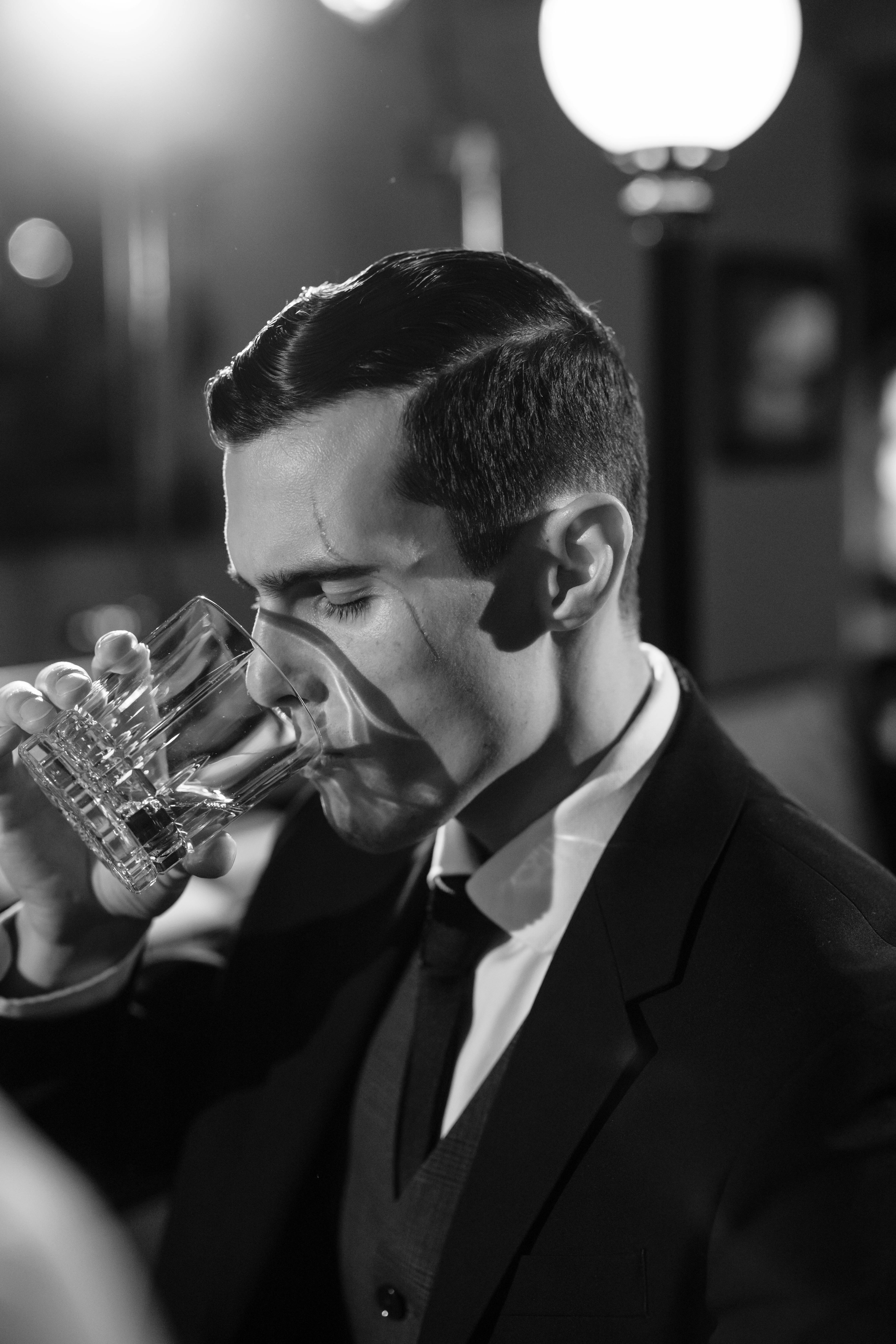 monochrome photo of man drinking whiskey