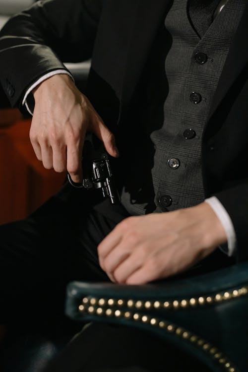 Photo of Person in Black Suit Holding Gun