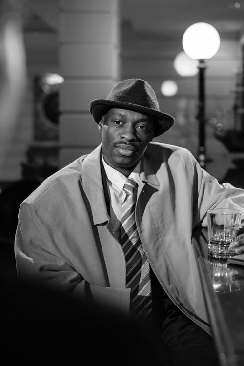 Free Moody black and white noir scene with detective in fedora at bar counter. Stock Photo