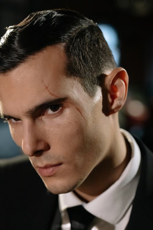Free Close-up portrait of a mysterious man with a scar, conveying a moody and enigmatic vibe. Stock Photo