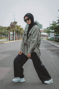 Stylish young woman in hijab posing on a city street in a fashionable outfit.