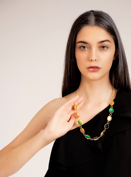 A Woman in Black Sleeveless Top Wearing Gold and Green Beaded Necklace