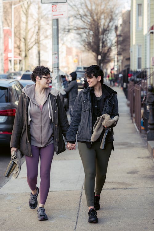 Content adult lesbian couple holding hands and walking on street