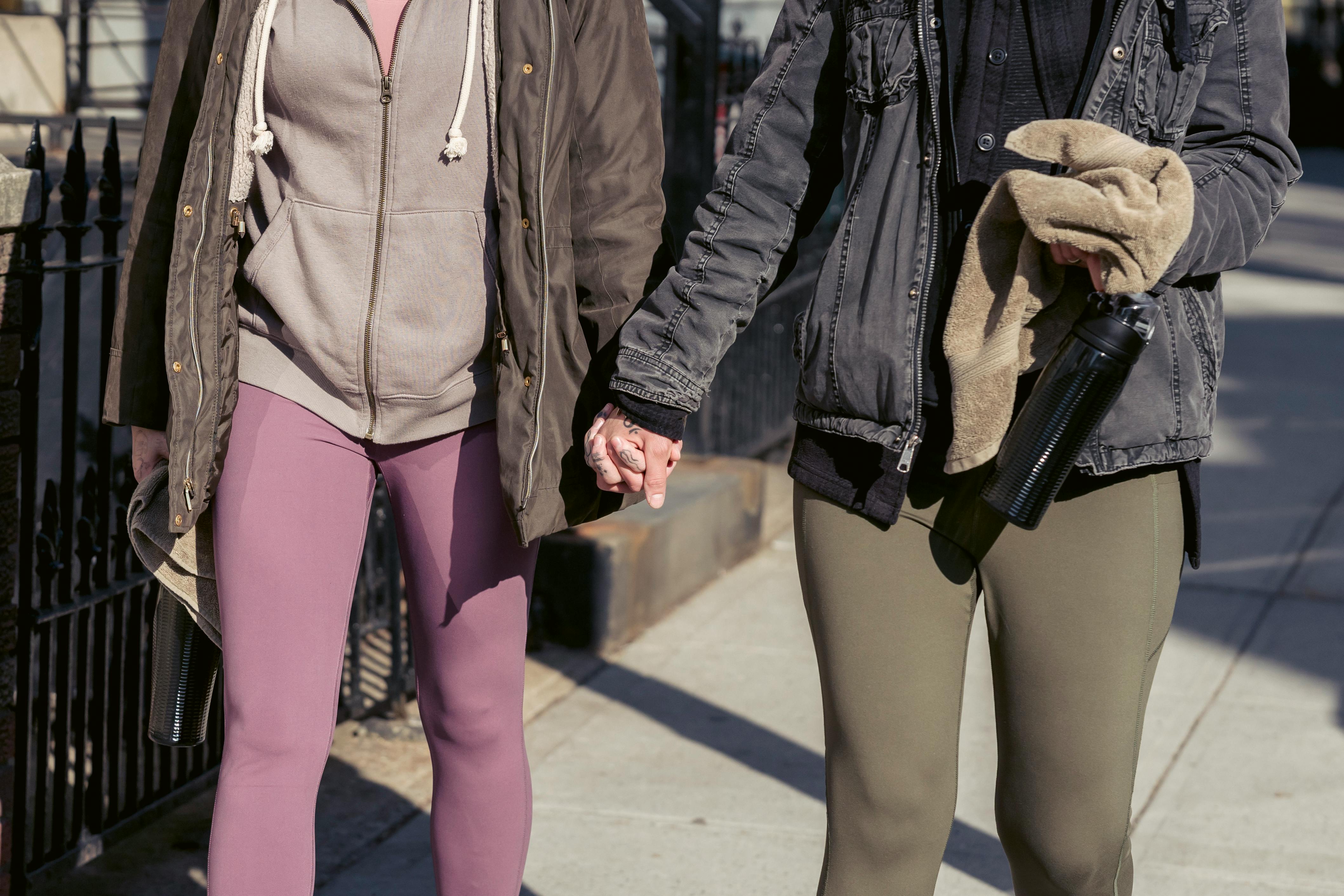 crop unrecognizable lesbian couple holding hands and walking on street