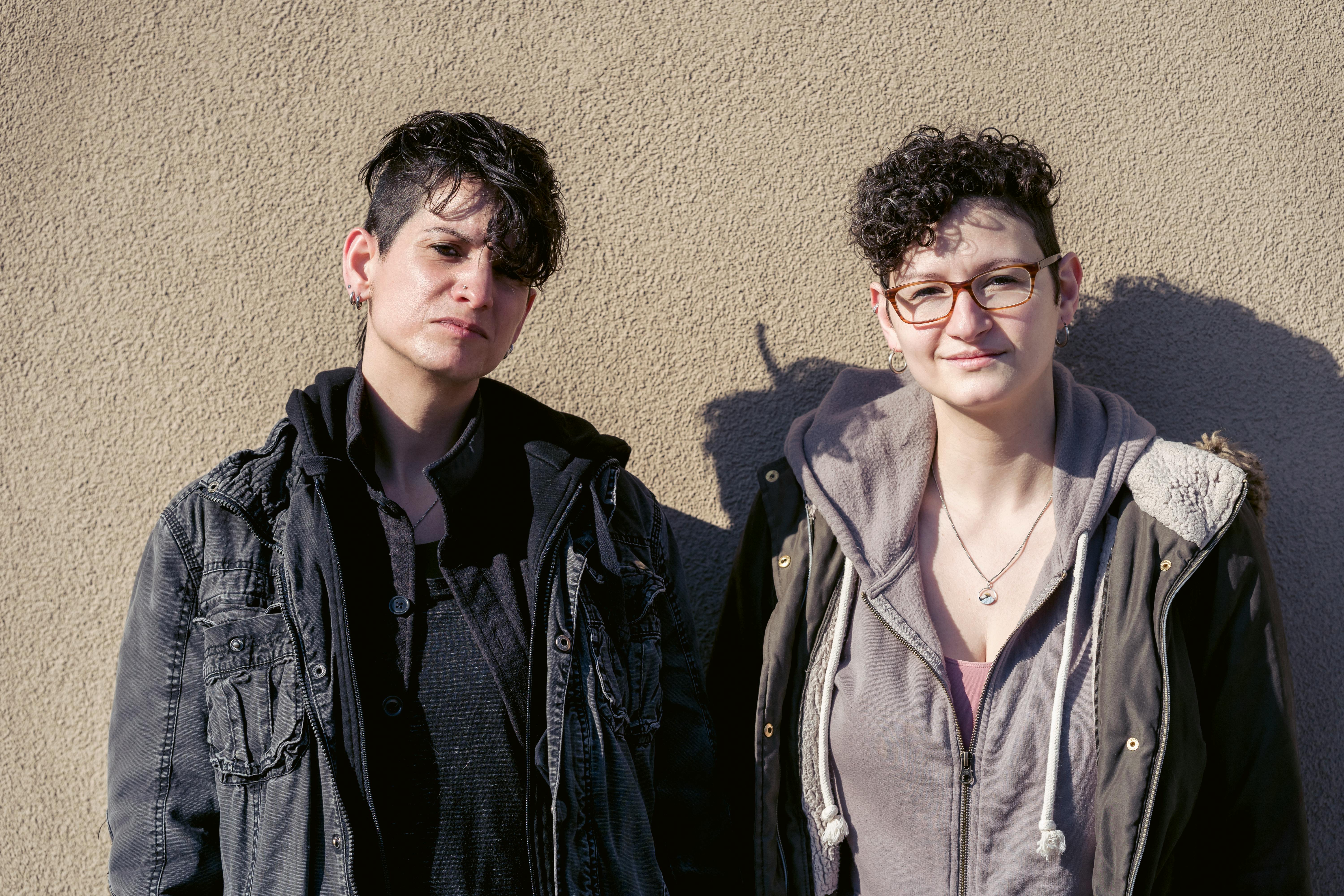 adult lesbian couple in outerwear standing on sunny street