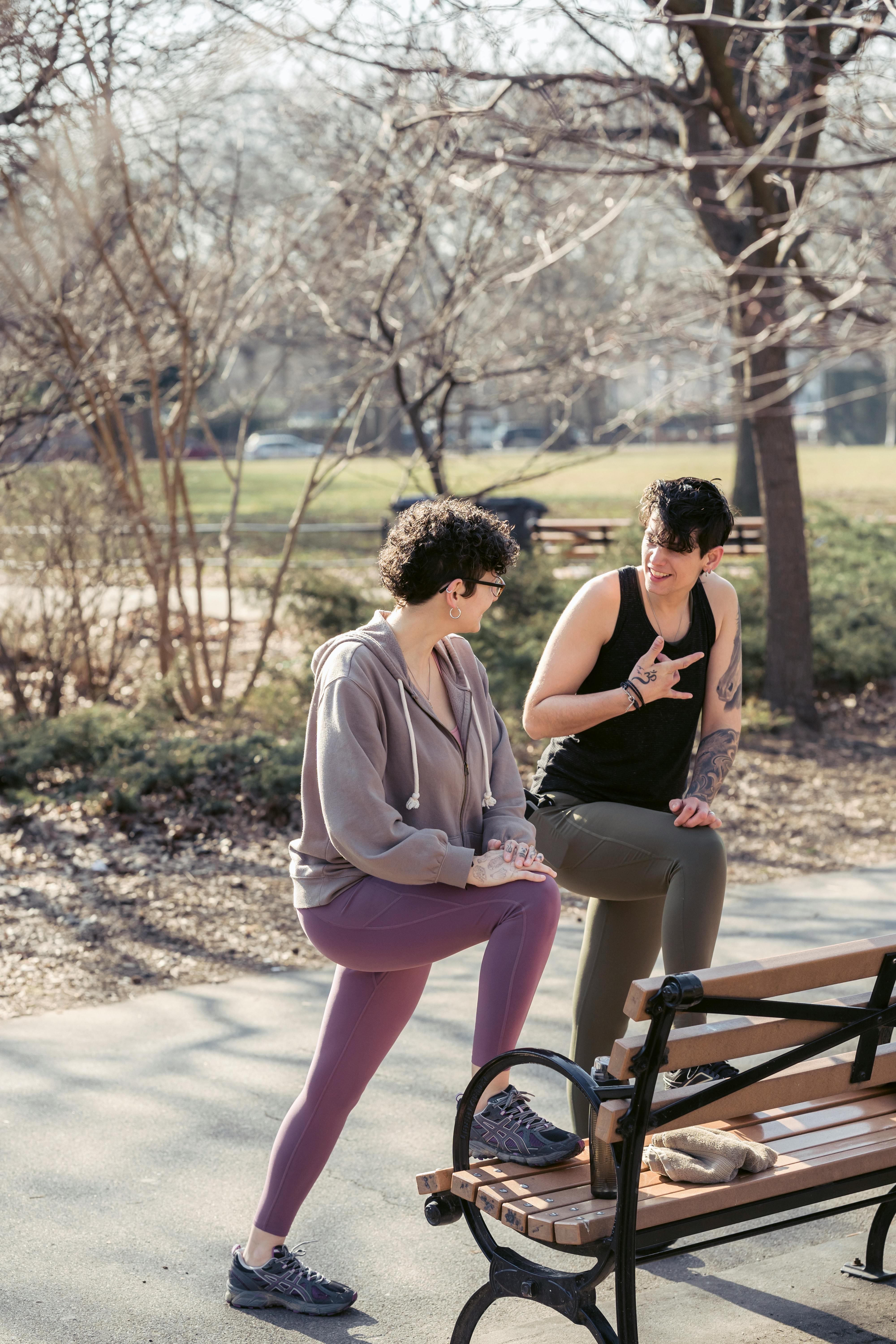 cheerful sportswomen stretching legs in autumn park