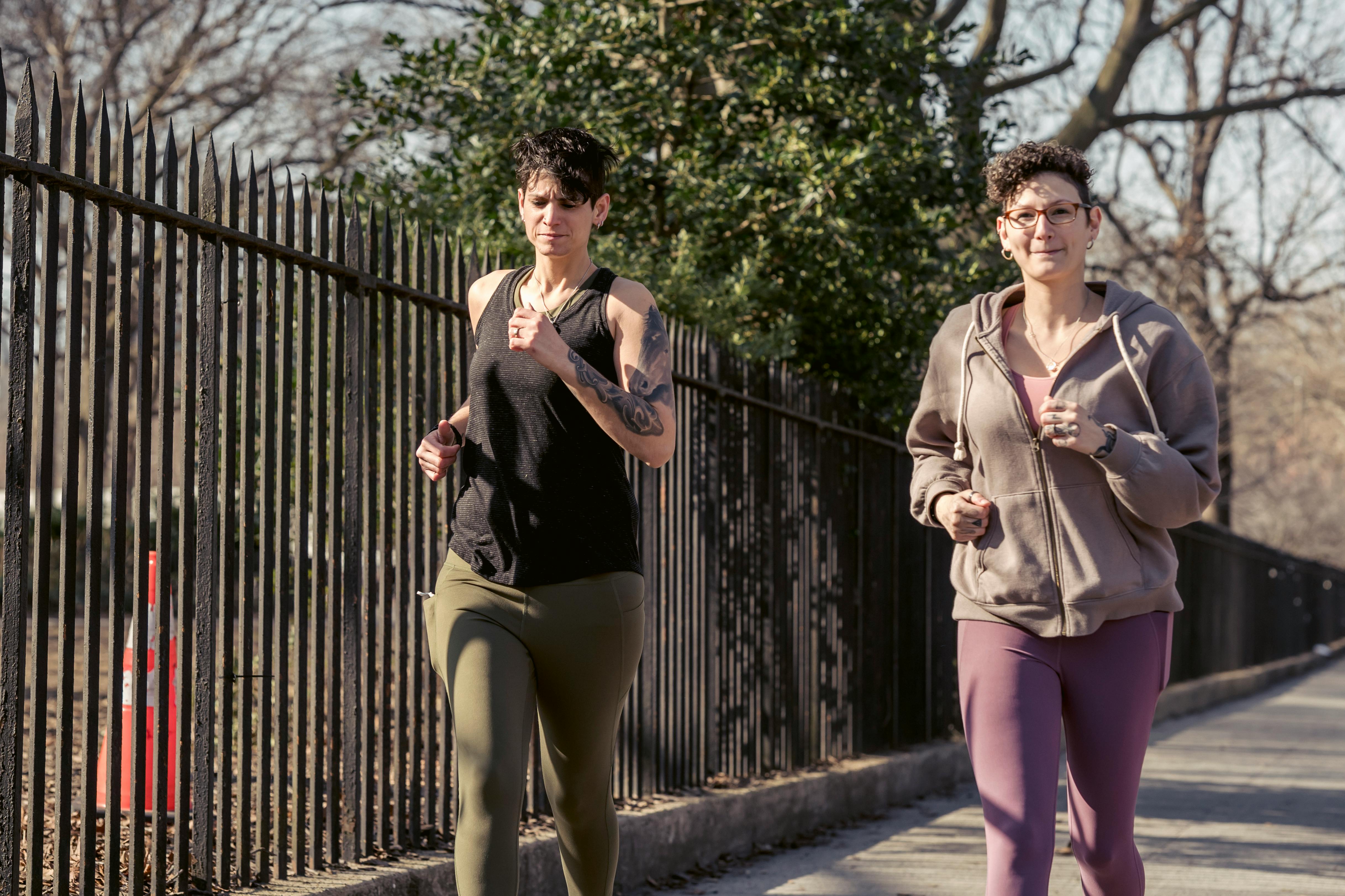 adult sportswomen jogging together on street