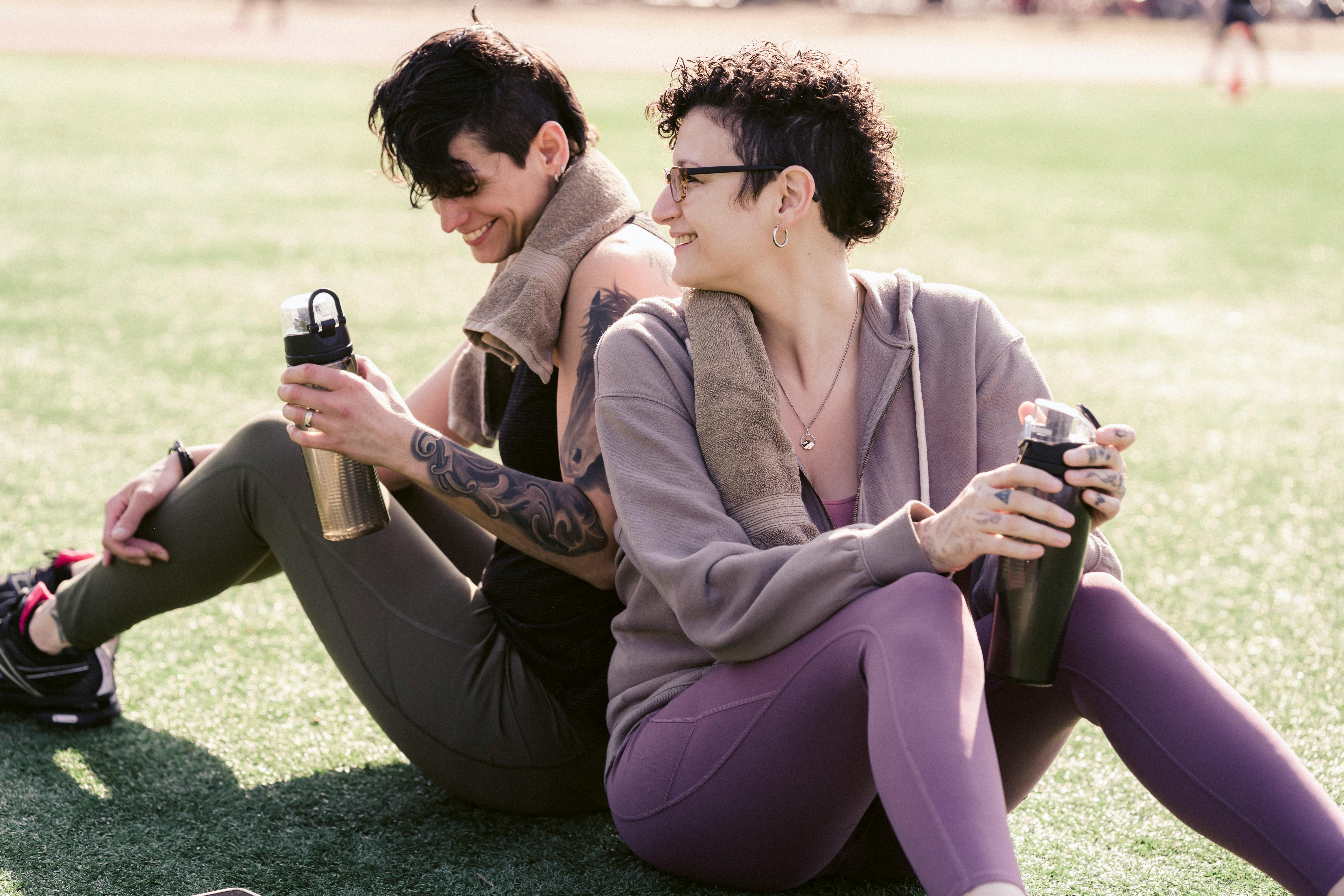 sportswomen drinking water on grass