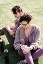 From above of couple of athletic girlfriend bending knee while stretching and relaxing on grass in daytime