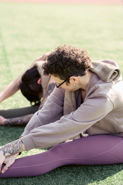 Free Unrecognizable people doing yoga on lawn Stock Photo