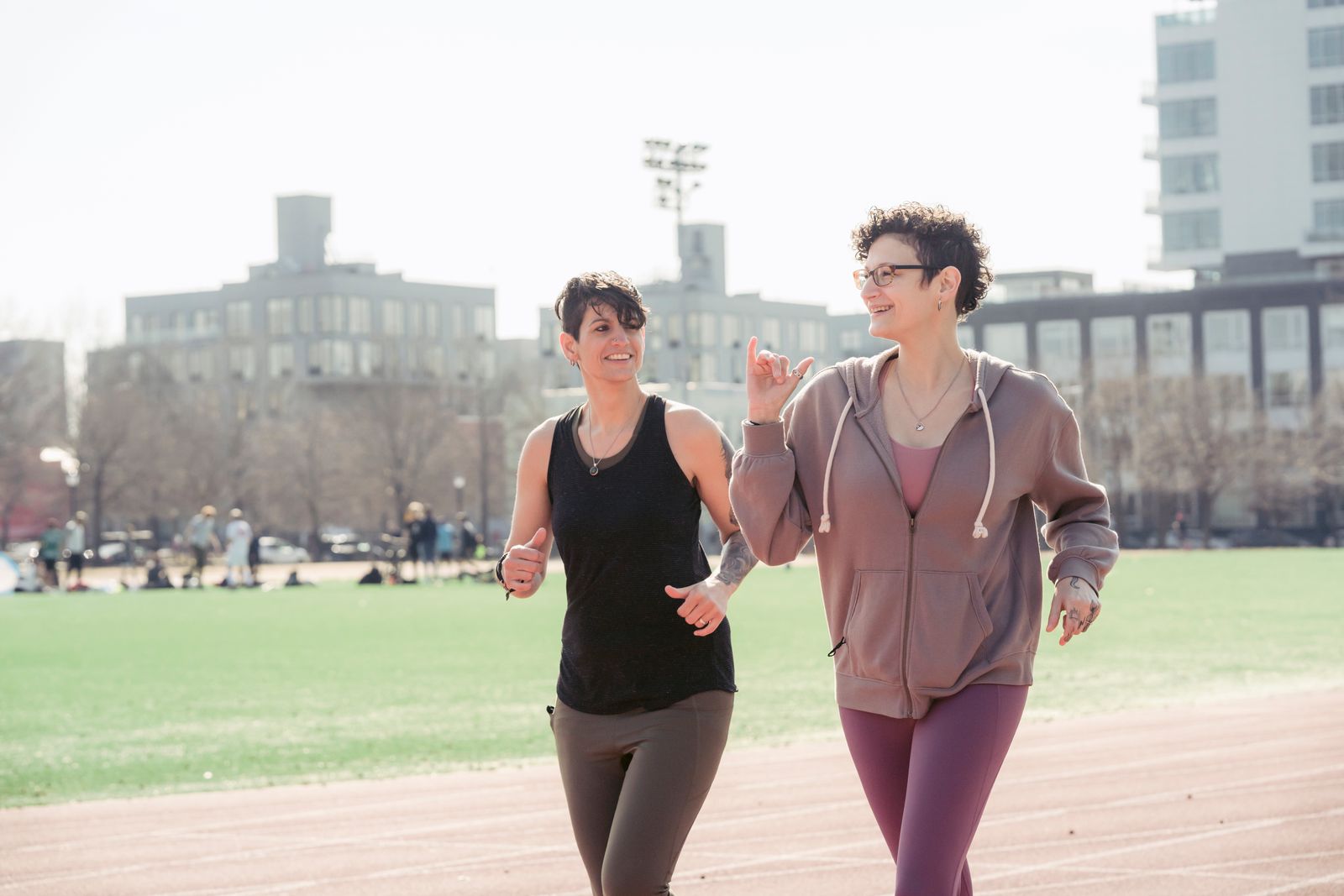 Two women jogging together on a sunny track