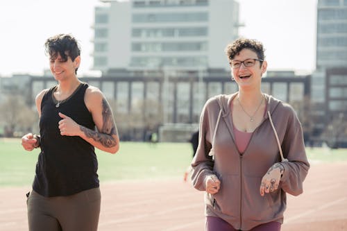 Free Positive young women running on sports ground in city Stock Photo