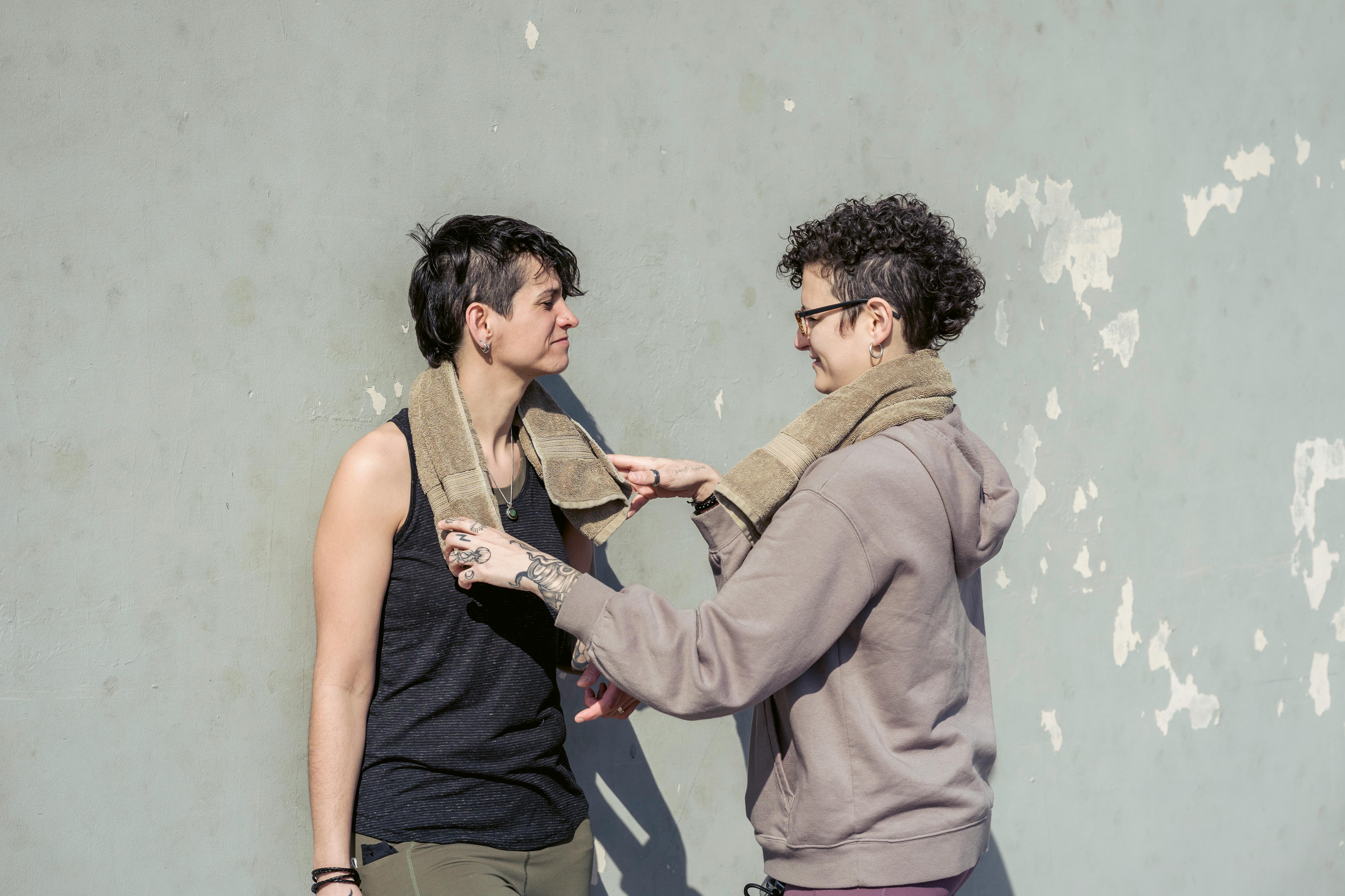 positive lesbian couple wiping sweat with towels after outdoor training