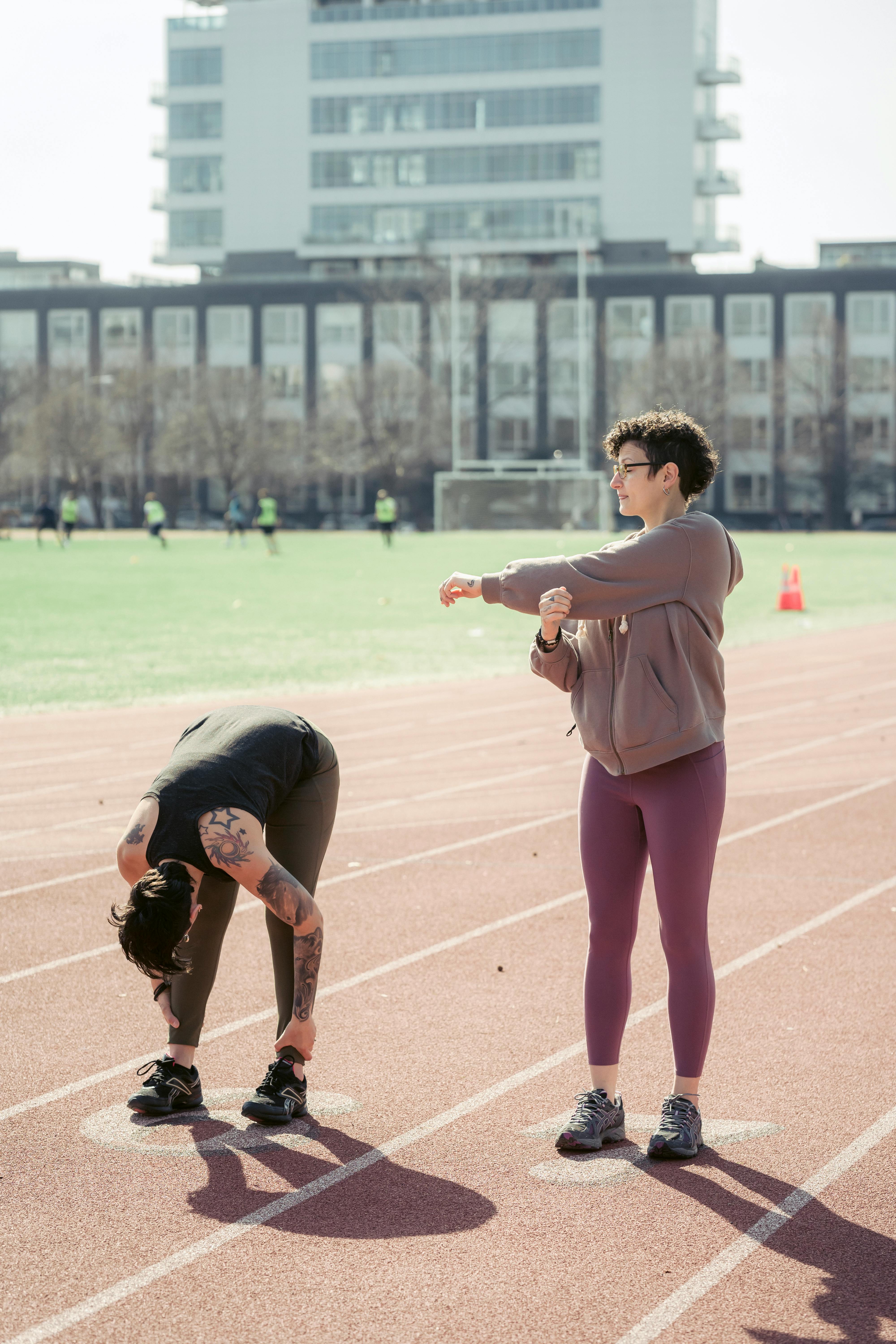 active sportswomen stretching body before running in city stadium