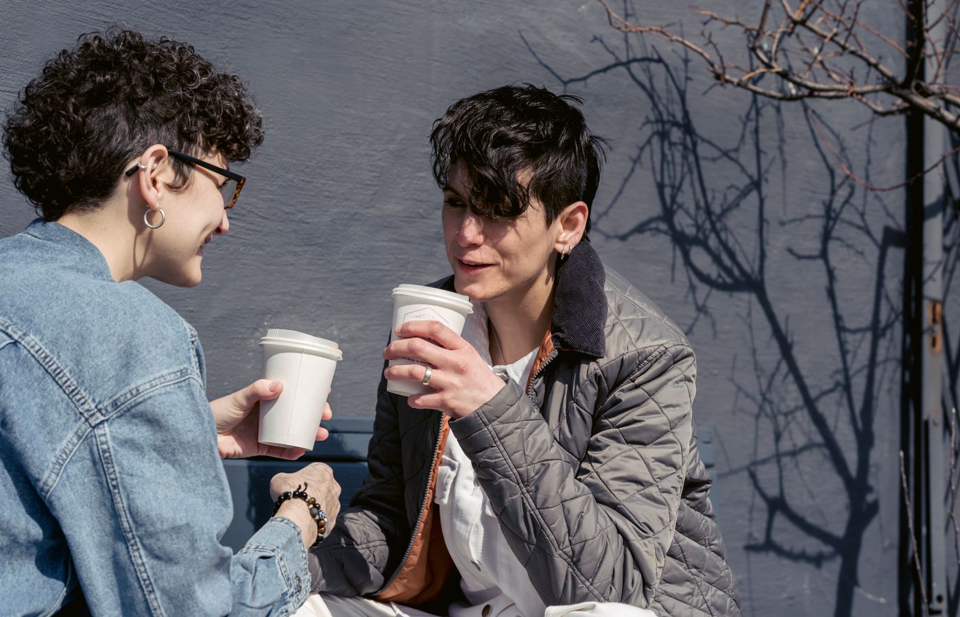 Two friends enjoying a coffee together outdoors, chatting and smiling.
