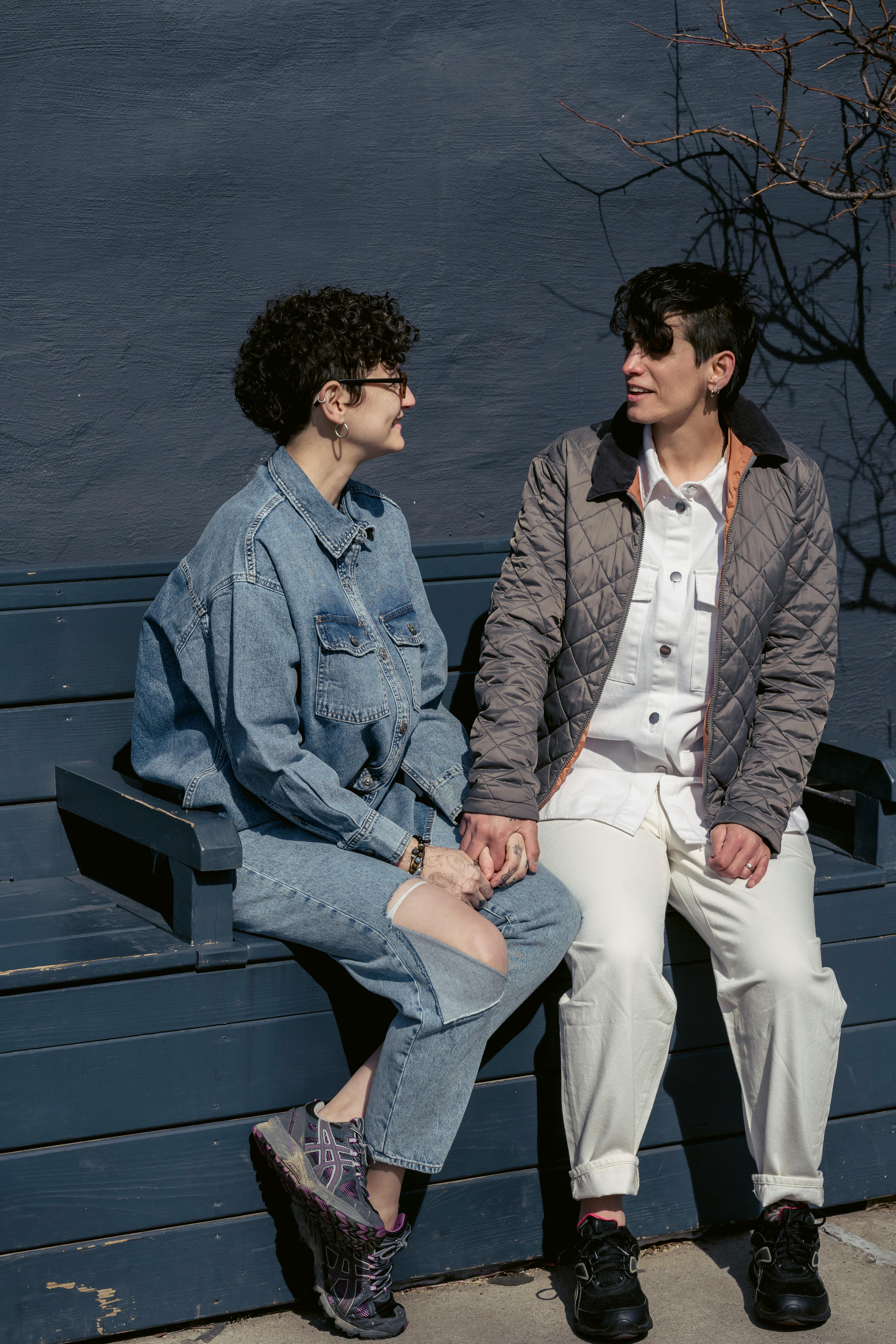 relaxed young homosexual women holding hands and chatting during date on street