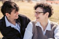 Joyful young lesbian couple laughing and hugging on lawn in park