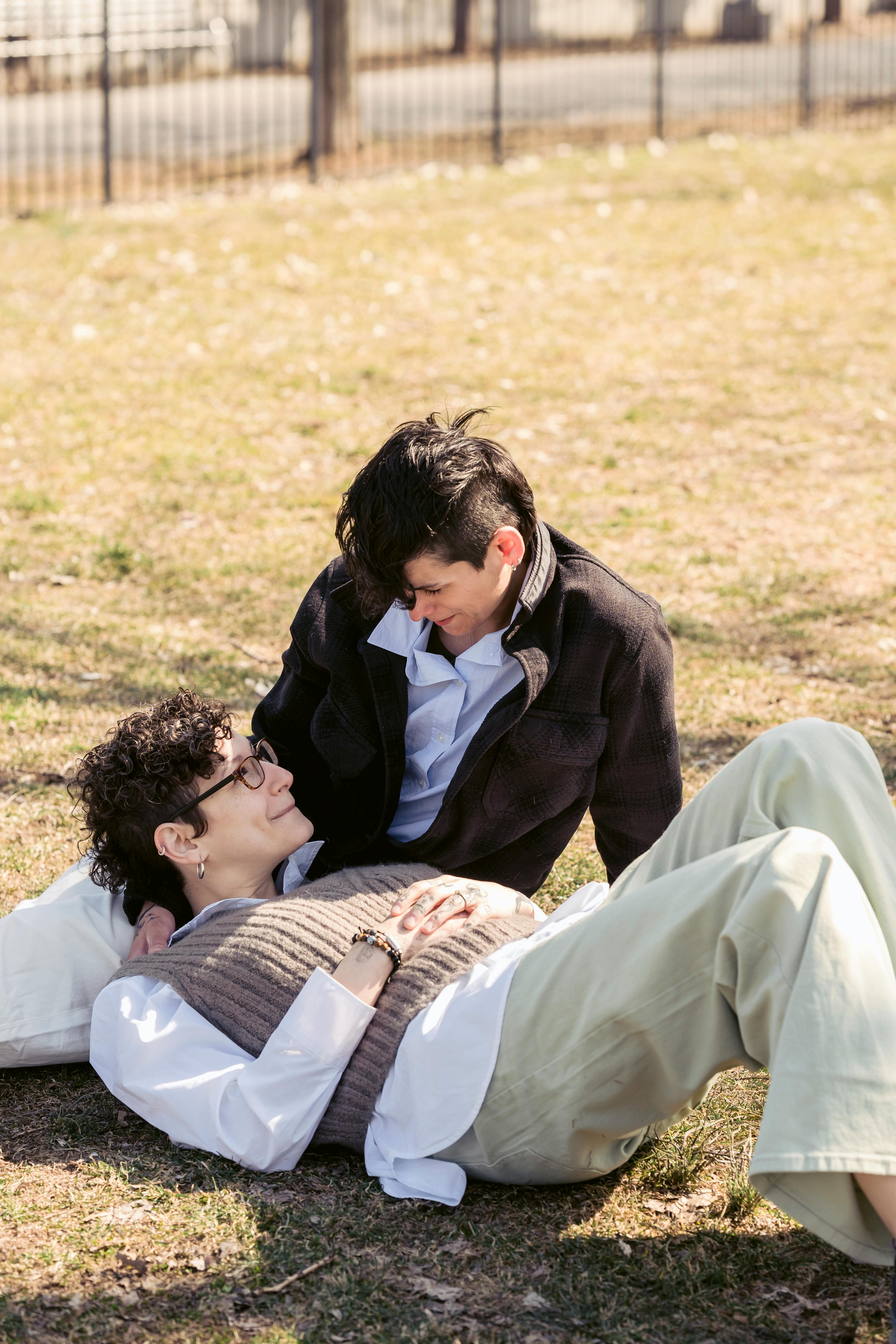 loving lesbian couple relaxing on grass in city park on sunny day